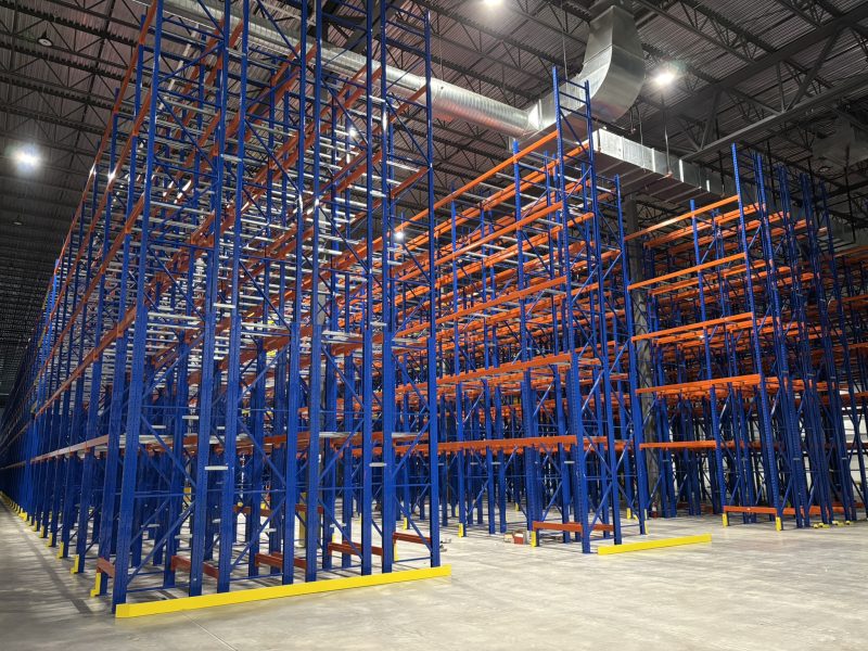 Installation de racks d’entrepôt industriels en acier bleu et orange à grande hauteur.